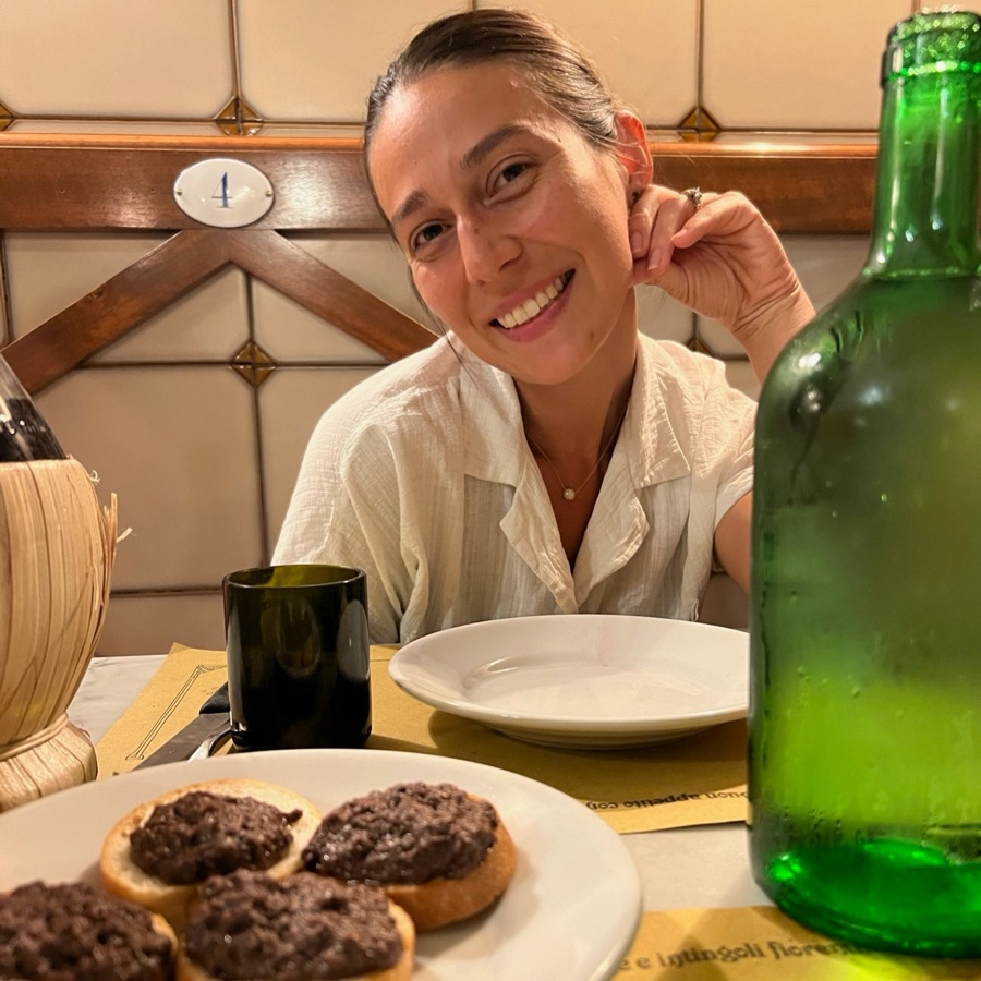 Amie smiling at a trattoria table in Italy with crostini toscani